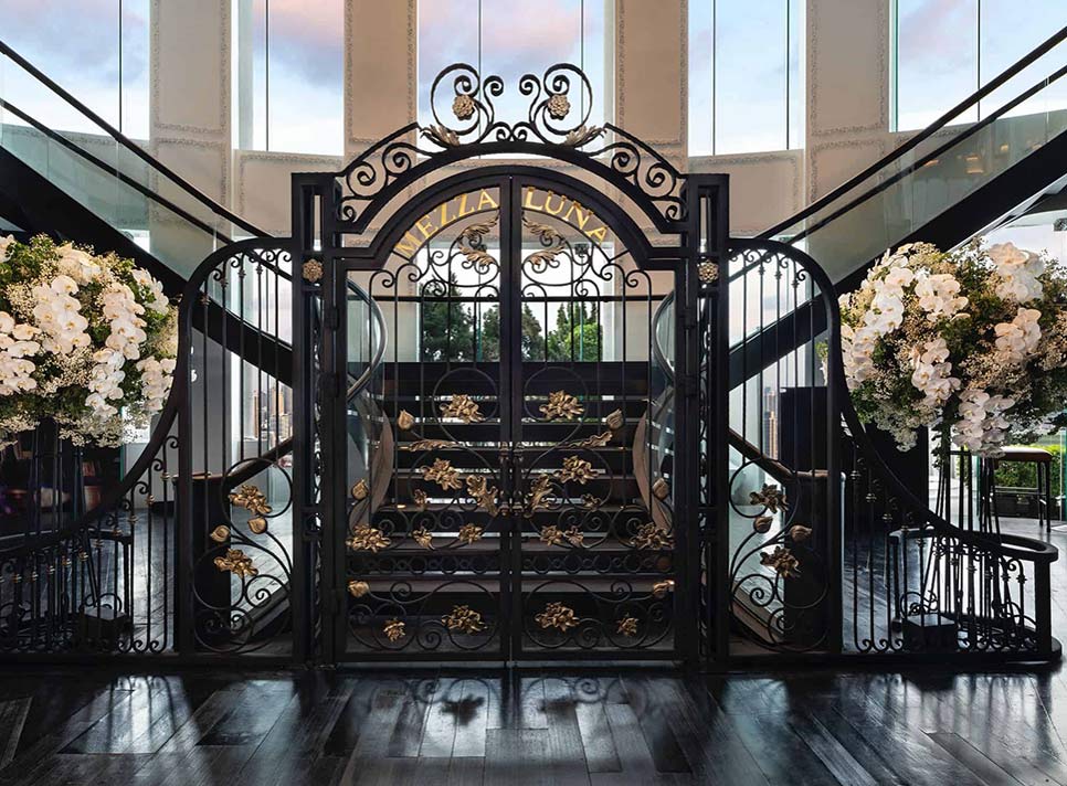 A majestic black gate with white flowers and black stairs on both sides