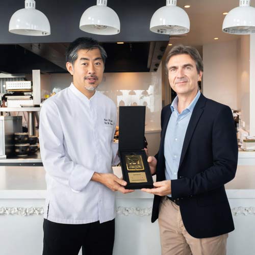 Chef and representative holding an award inside the professional kitchen at Mezzaluna restaurant, Lebua Hotels and Resorts, equipped with Electrolux Professional solutions