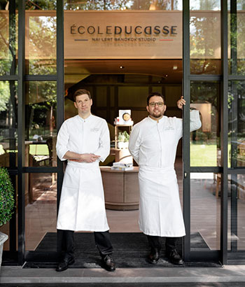 Two chefs standing at the entrance of École Ducasse Nai Lert Bangkok Studio, equipped with Electrolux Professional kitchens