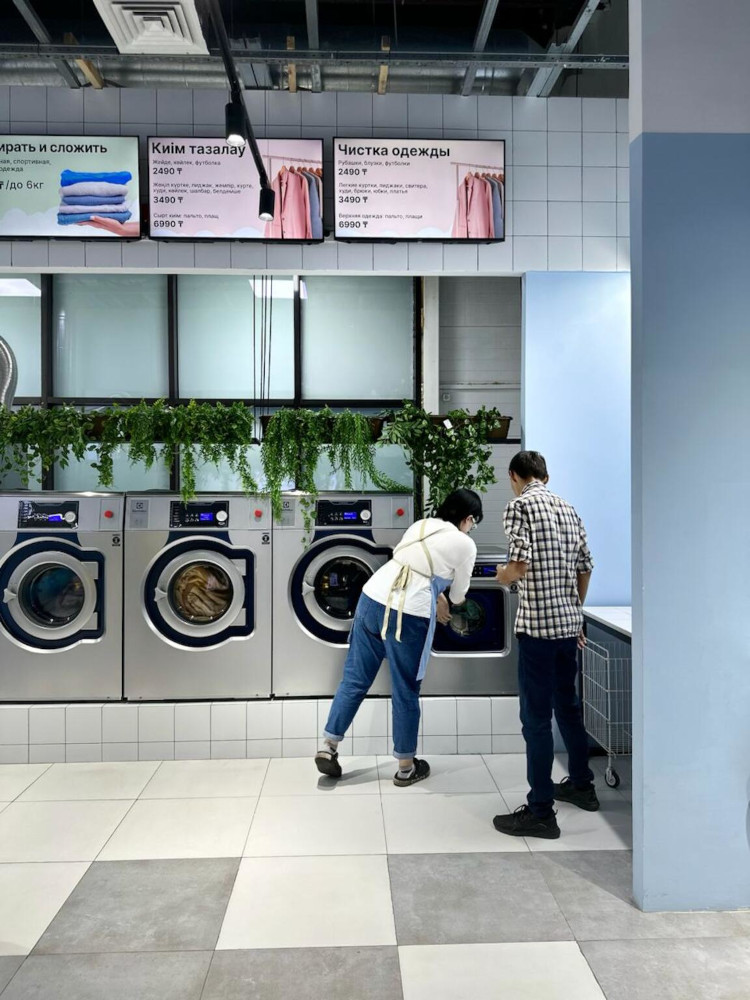 Two people operating Electrolux Professional laundry machines in Mamalama’s self-service laundry
