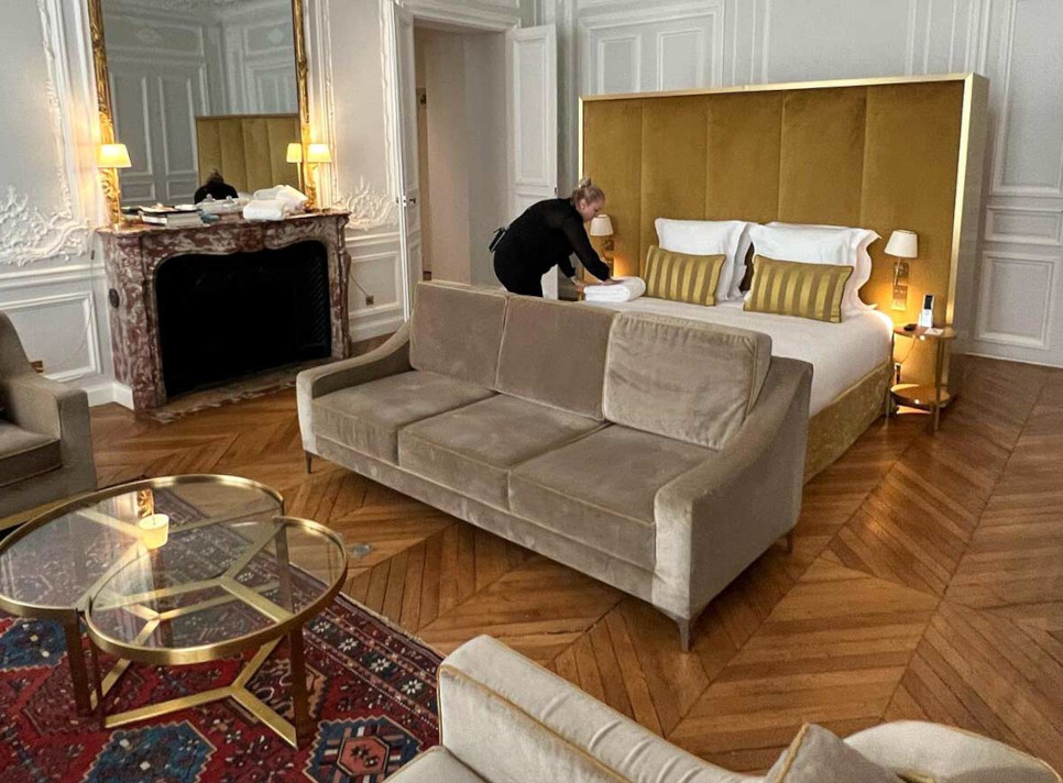 Luxurious hotel bedroom with a woman tidying up the bed
