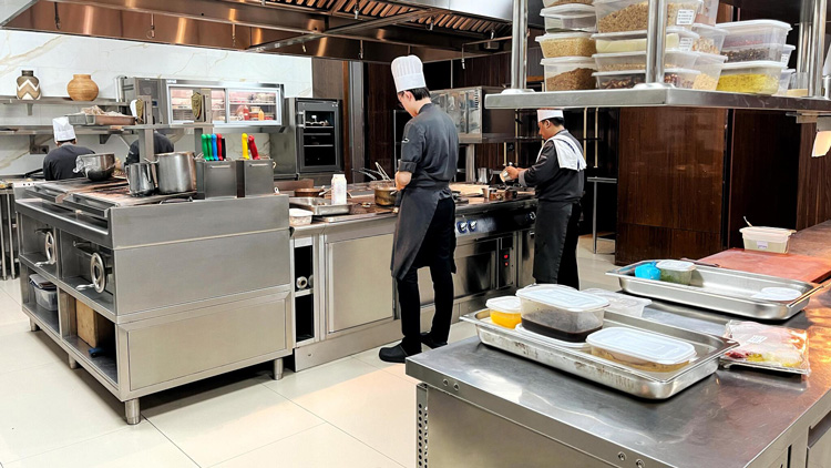 Two chefs preparing food in modern professional kitchen at Raffles Hotel Jakarta with Electrolux Professional equipment