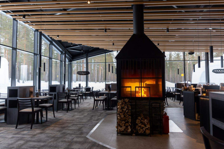 Modern dining area at hotel resort featuring central fireplace and large windows with scenic views