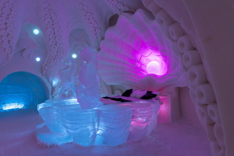 Ice room with sculpted walls and glowing colored lights inside hotel resort Snowvillage winter experience