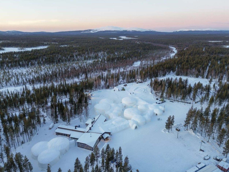 Aerial view of hotel resort buildings in winter landscape surrounded by forest and snow