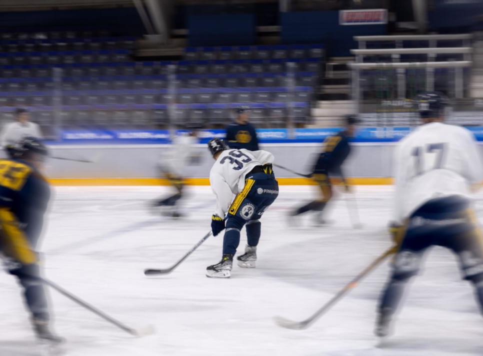 Ice hockey players in motion during a game on an indoor rink.