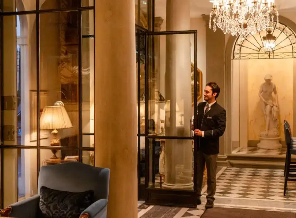 Hotel staff welcoming guests at entrance of luxury hotel with elegant interior design