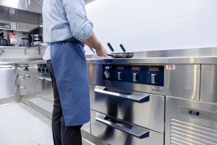 Professional cooking station with working chef, equipped with stainless steel equipment