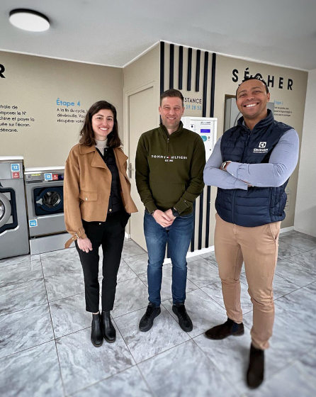 Three people standing inside St Omer Laundromat with Electrolux Professional washing machines in the background